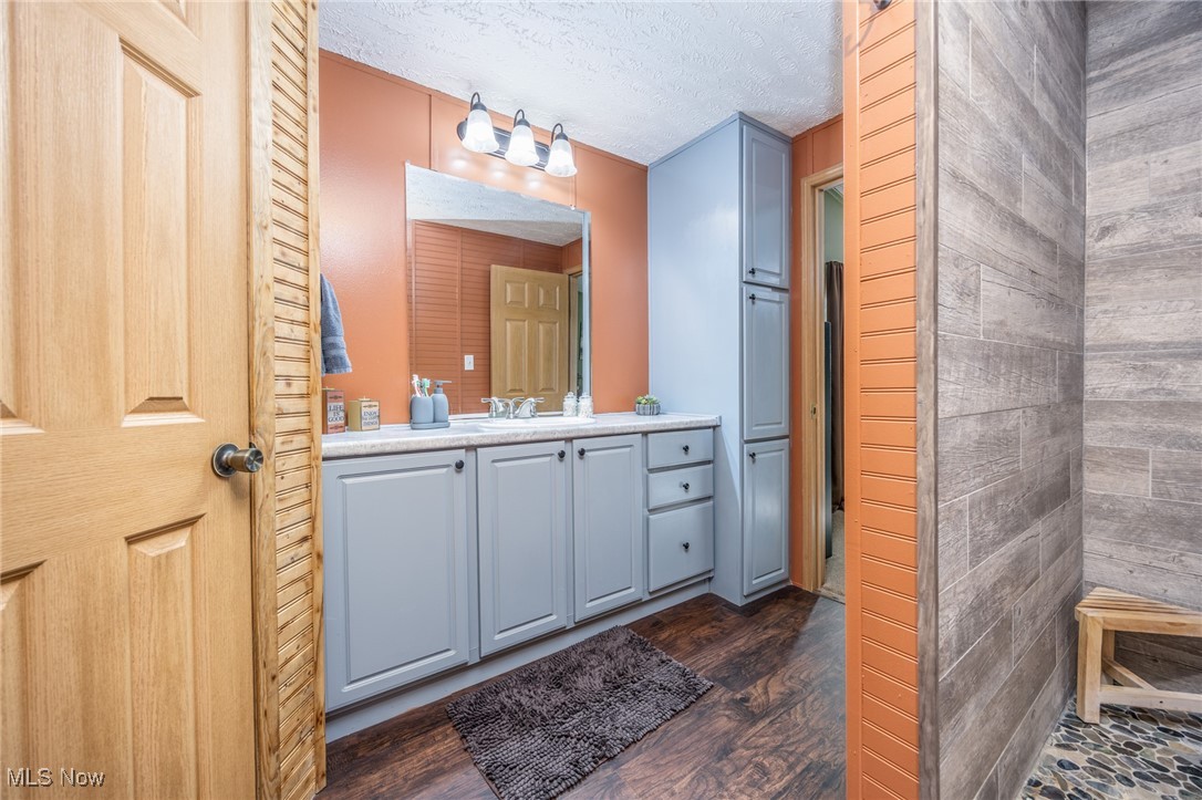 1788 Rosenbush Road Newport, OH 45768 - Photo 22 of 34 Bathroom with vanity, dark wood finished floors, a textured ceiling, and wood walls
