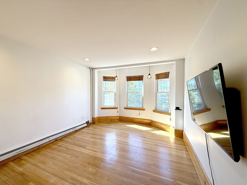 148 Berkshire Street, Unit 4 Cambridge, MA 02141 - Photo 4 of 17 a view of empty room with wooden floor and fan