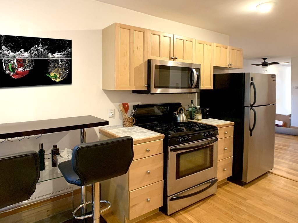 148 Berkshire Street, Unit 4 Cambridge, MA 02141 - Photo 9 of 17 a kitchen with stainless steel appliances a stove microwave and a refrigerator