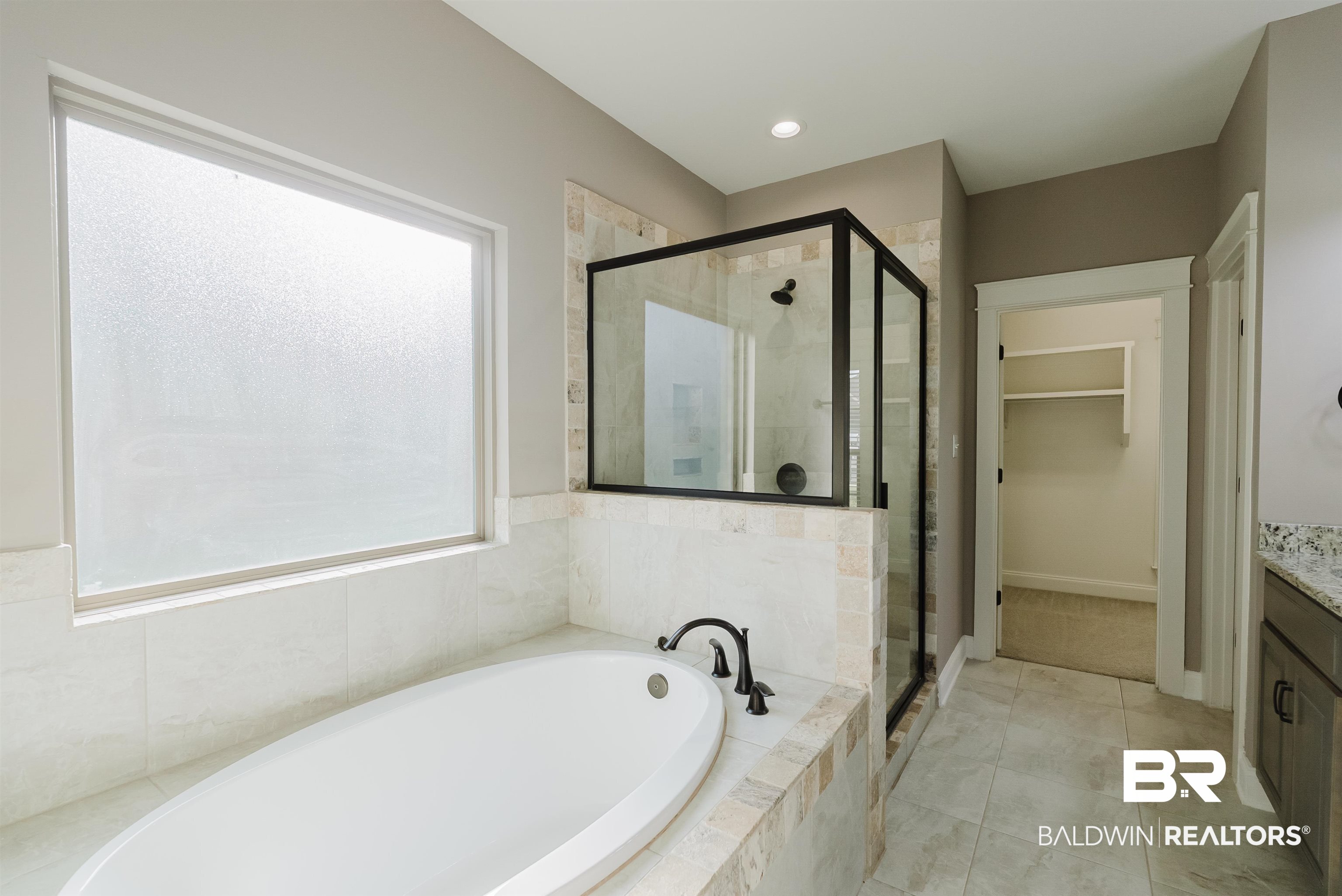 237 Hawthorne Circle Fairhope, AL 36532 - Photo 8 of 14 Full bathroom featuring vanity, a spacious closet, a shower stall, light tile patterned flooring, and a garden tub