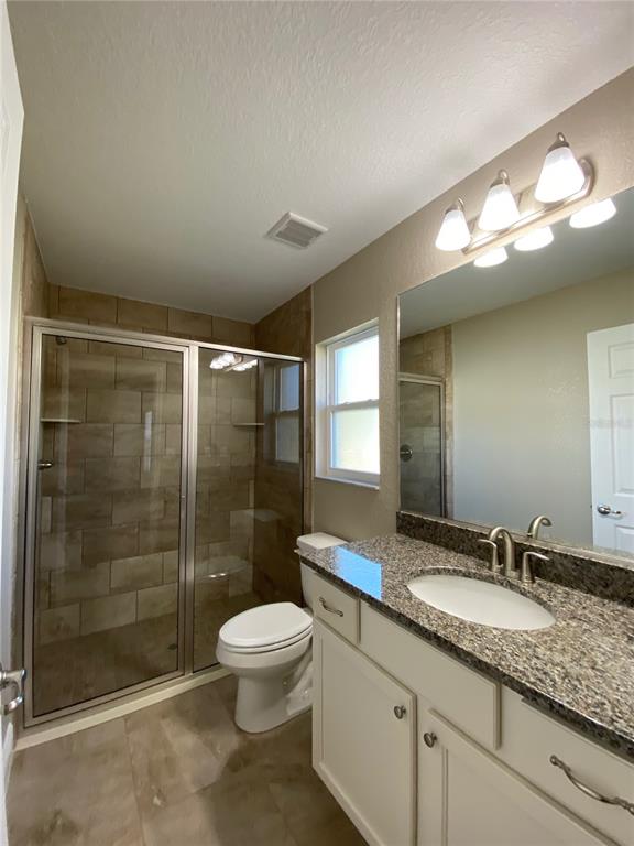 4110 Southwest 132nd Lane Ocala, FL 34473 - Photo 25 of 30 a bathroom with a granite countertop sink a toilet a mirror and shower