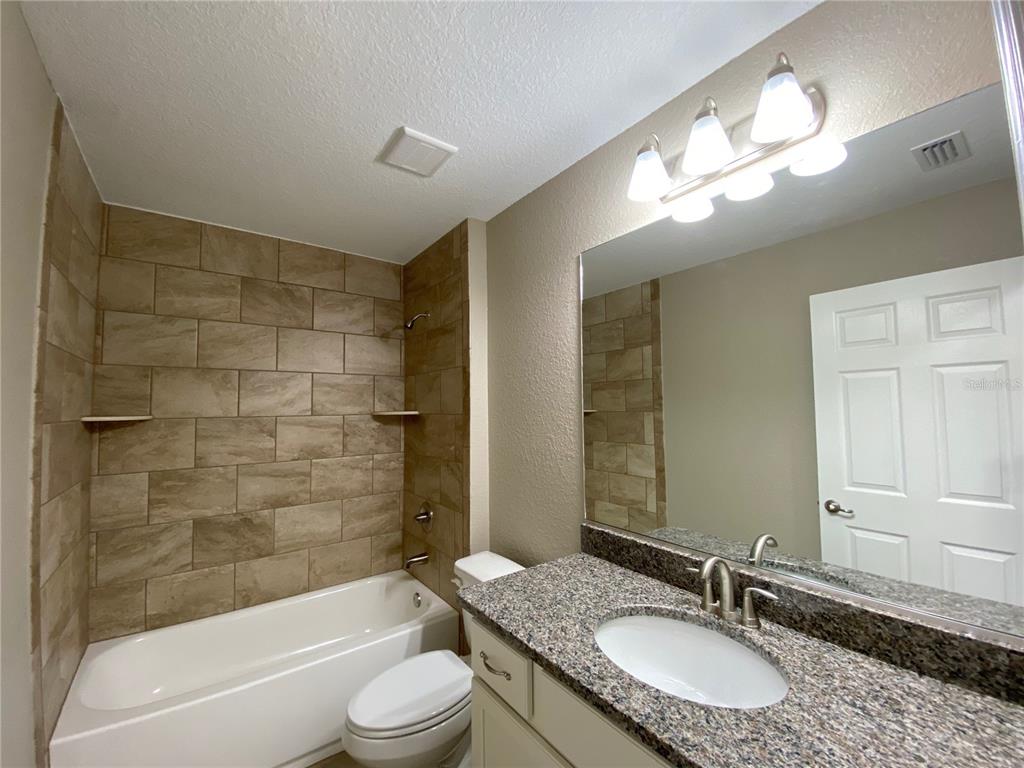 4110 Southwest 132nd Lane Ocala, FL 34473 - Photo 28 of 30 a bathroom with a granite countertop sink toilet mirror and bathtub