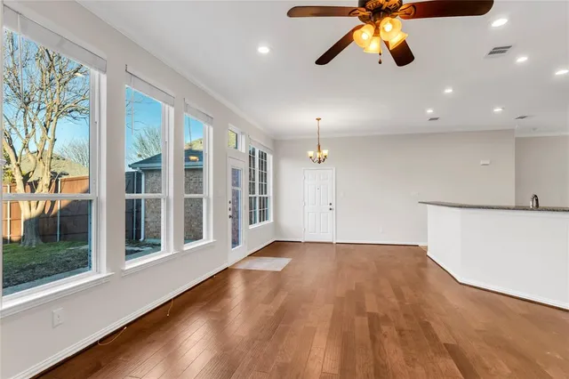 a view of an empty room with window and wooden floor
