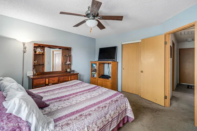 a bedroom with a large bed a flat tv screen and dresser