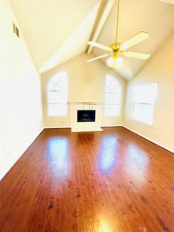 an empty room with wooden floor fan and windows