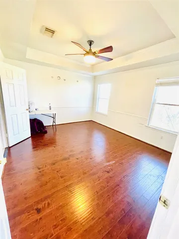a view of empty room with wooden floor and fan