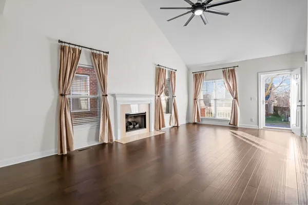an empty room with wooden floor fireplace and windows