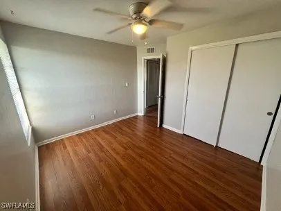 an empty room with wooden floor and fan