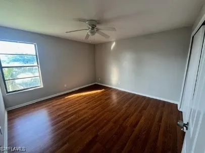 an empty room with wooden floor fan and windows