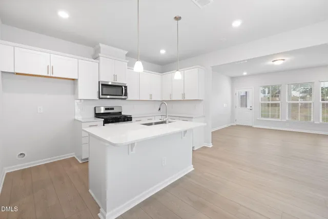 a kitchen with kitchen island a sink stainless steel appliances and white cabinets