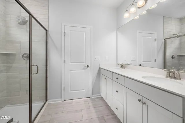 a spacious bathroom with a double vanity sink a large mirror and shower