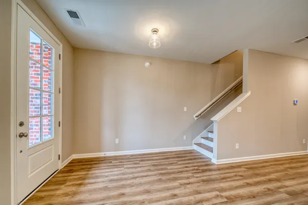a view of an empty room with a window and wooden floor