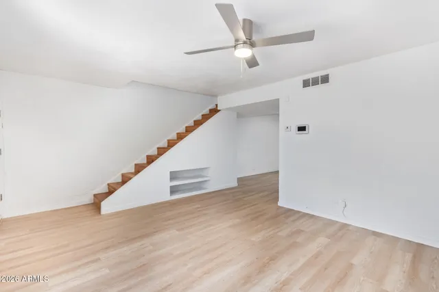 a view of an empty room with wooden floor and stairs