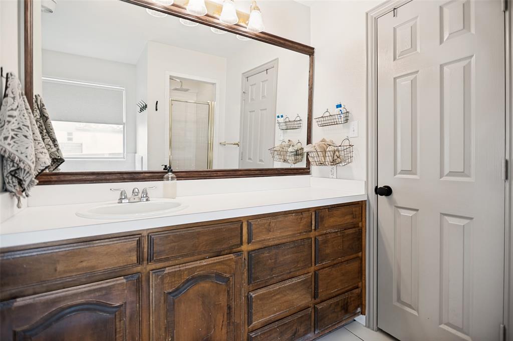 5643 West Caylor Road Fort Worth, TX 76244 - Photo 20 of 37 Bathroom vanity featuring a wood-finish base, white countertop, and integrated sink