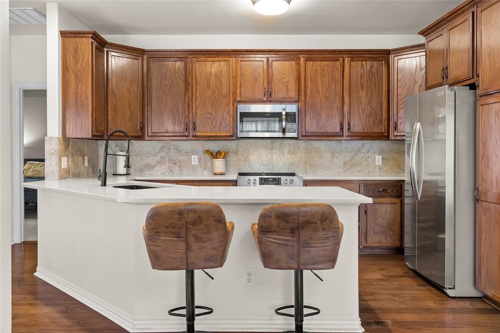 1308 Madeline Street Commerce, TX 75428 - Photo 15 of 37 a kitchen with stainless steel appliances granite countertop a refrigerator a stove a sink and a counter space