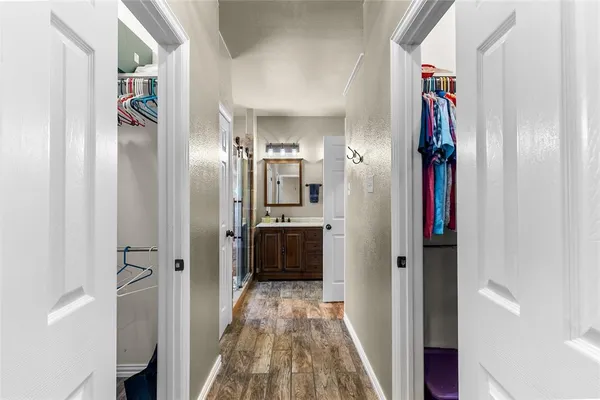 a view of a hallway with wooden floor and a bathroom