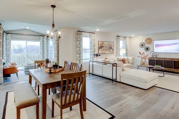 a view of a dining room and livingroom with furniture wooden floor a chandelier