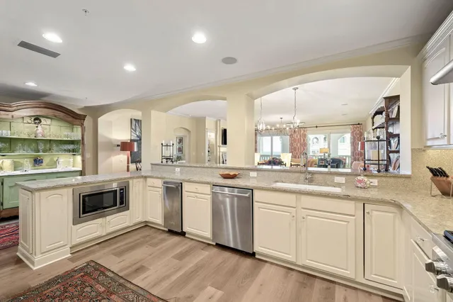 a large white kitchen with stainless steel appliances granite countertop a stove and white cabinets
