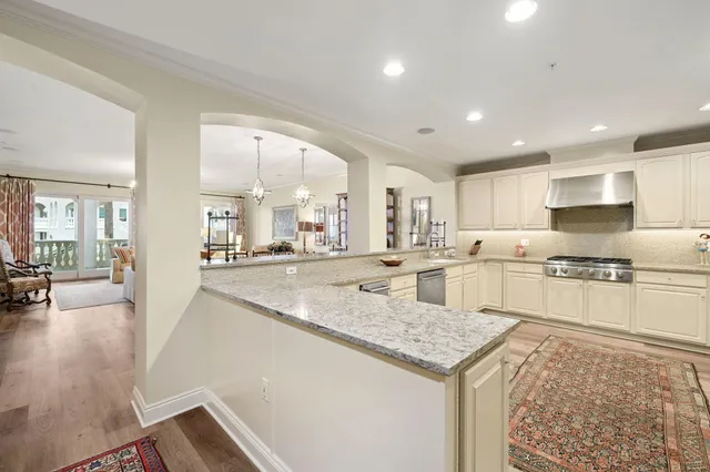 a kitchen with a stove a sink a refrigerator and white cabinets with wooden floor