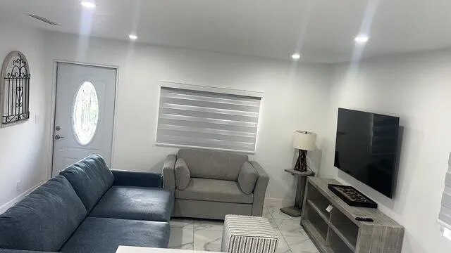 a living room with furniture a flat screen tv and a window