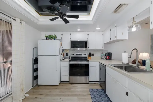 a kitchen with stainless steel appliances granite countertop a refrigerator a stove a sink dishwasher and a refrigerator with wooden floor