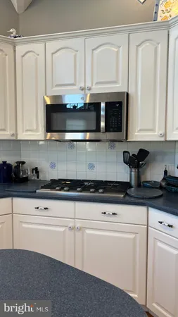 a kitchen with granite countertop white cabinets and stainless steel appliances