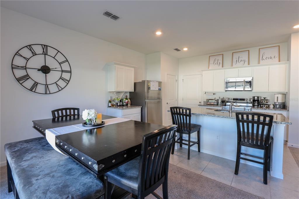 2240 Hemingway Circle Groveland, FL 34736 - Photo 16 of 34 a kitchen with stainless steel appliances granite countertop a table chairs and a refrigerator