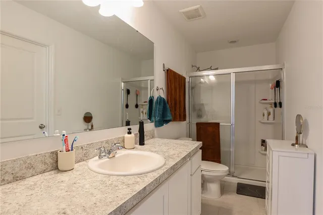 a bathroom with a granite countertop sink a toilet and a large mirror