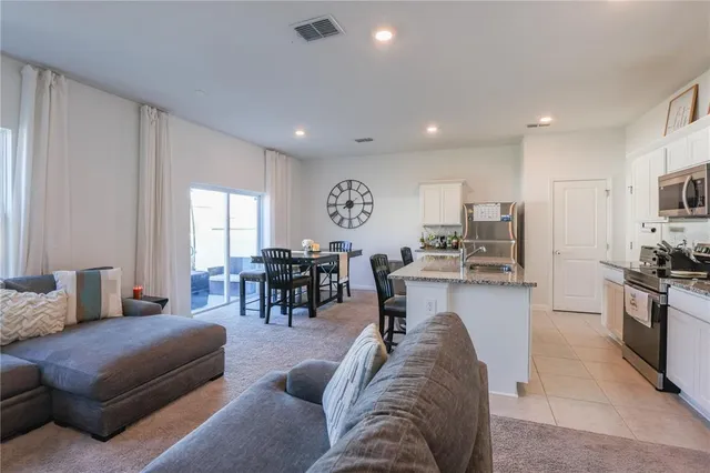 a living room with furniture kitchen view and a large window