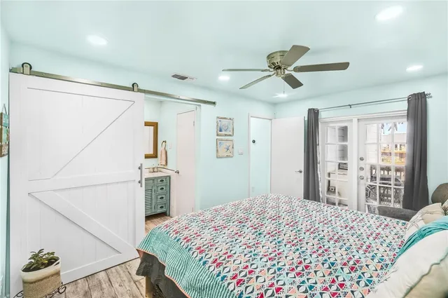 a bedroom with a bed ceiling fan and a wooden floor