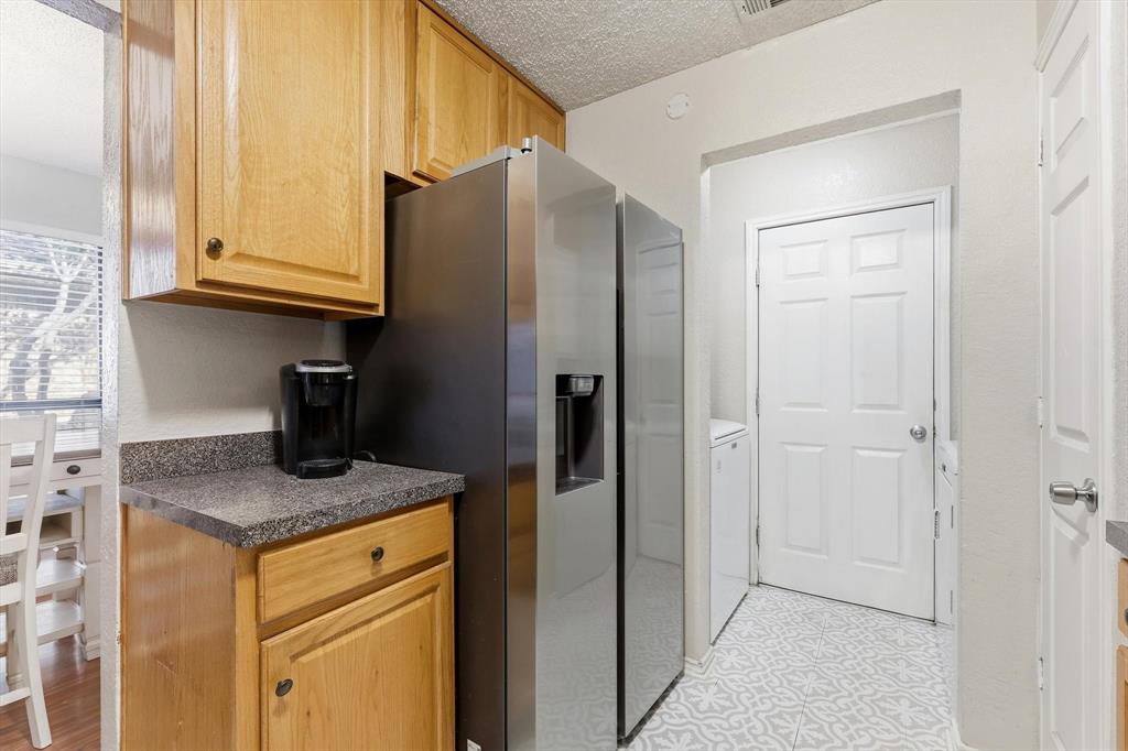 1312 Hackamore Street Mesquite, TX 75149 - Photo 10 of 23 Kitchen featuring dark countertops, a textured ceiling, stainless steel fridge with ice dispenser, washer / clothes dryer, and light flooring