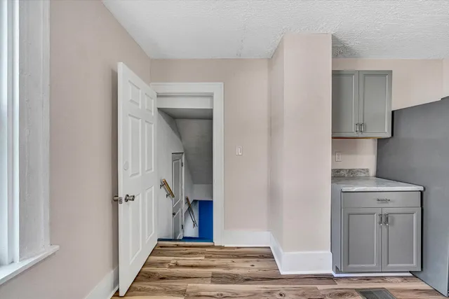 a view of an empty room with window and wooden floor