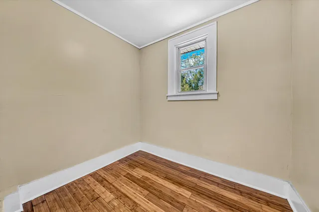 a view of an empty room with wooden floor and stairs