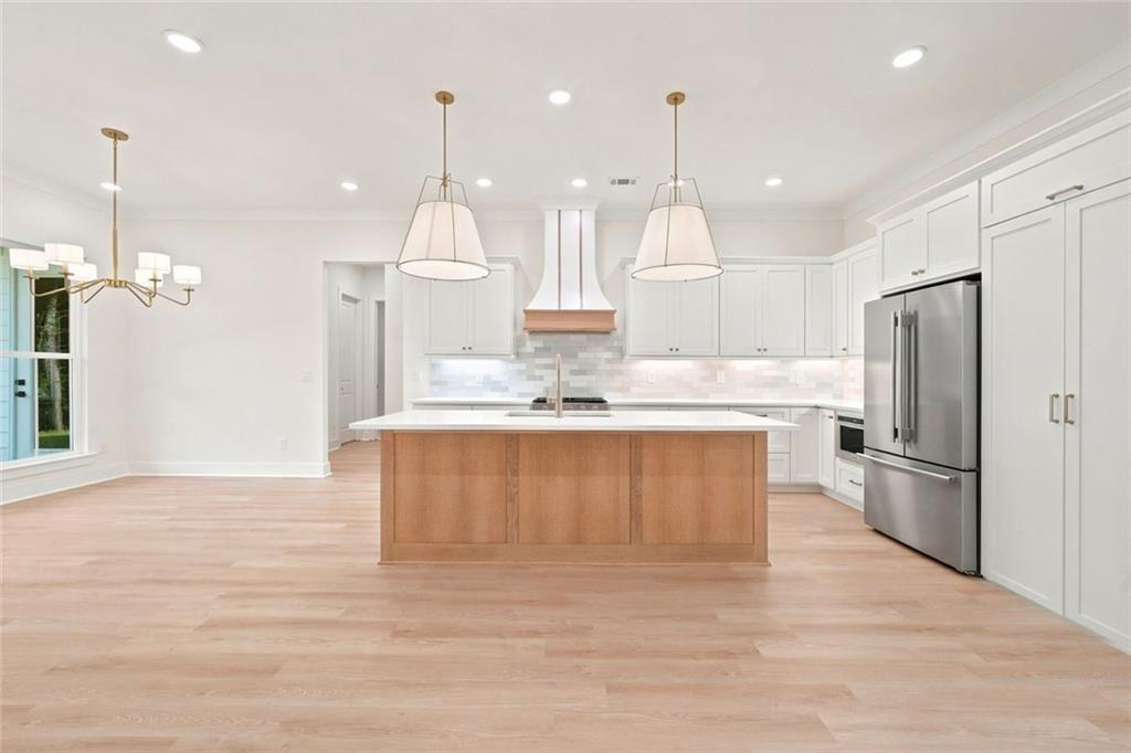 37 Kirk Road Northwest White, GA 30184 - Photo 14 of 55 a large kitchen with granite countertop a large kitchen island white cabinetry a refrigerator and a chandelier