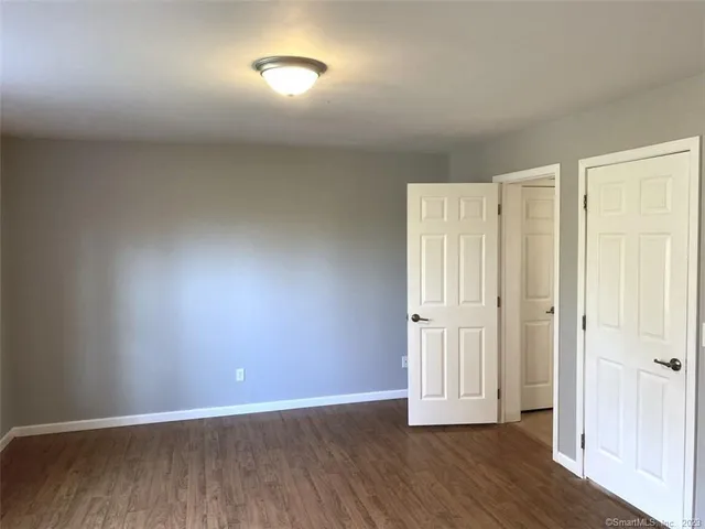 an empty room with wooden floor and mirror