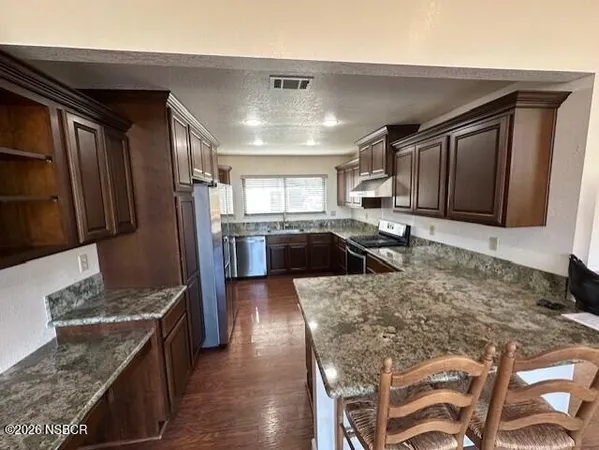 a large kitchen with granite countertop stainless steel appliances and wooden cabinets