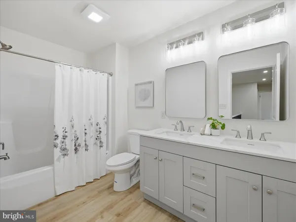 a bathroom with a double vanity sink toilet mirror and bathtub
