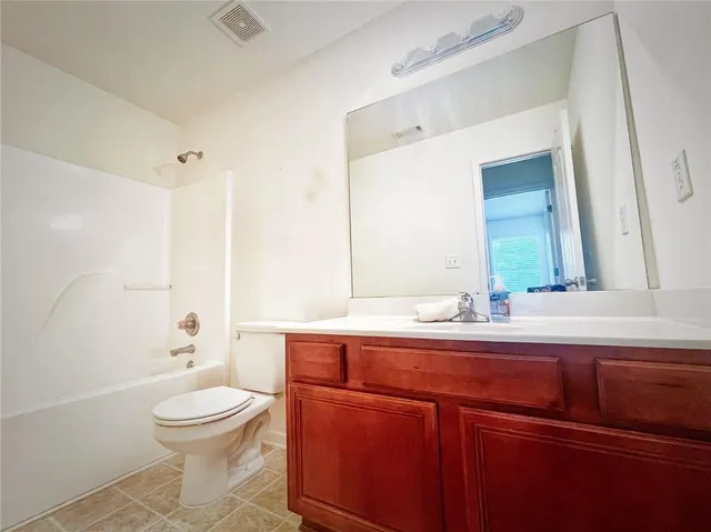 a bathroom with a granite countertop toilet a sink and a mirror