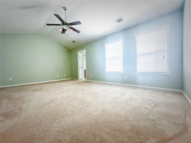 an empty room with a ceiling fan and windows
