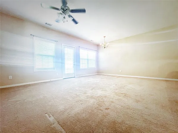 en empty room with windows and chandelier fan