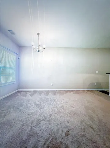 a view of an empty room and a chandelier fan