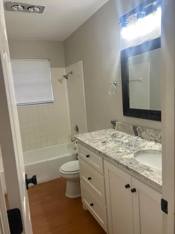 a bathroom with a granite countertop toilet a sink and a mirror