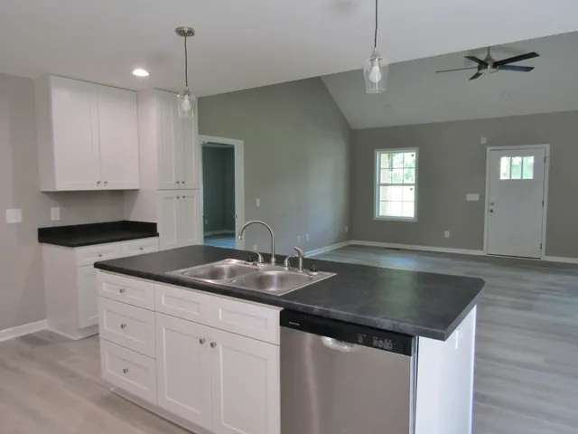 a kitchen with granite countertop a sink and white cabinets