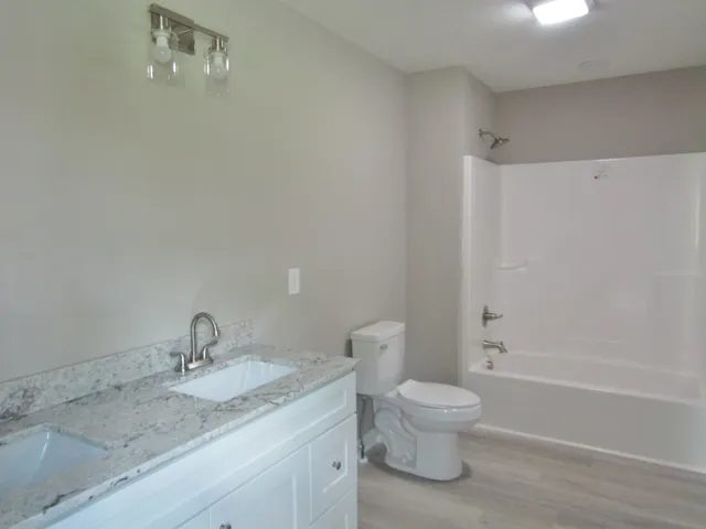 a bathroom with a granite countertop sink a toilet and shower
