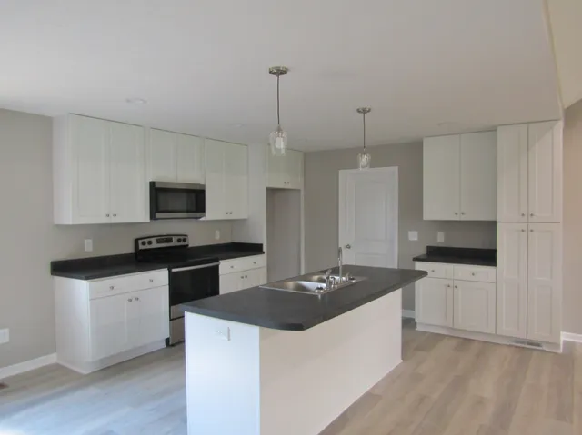 a kitchen with granite countertop a sink stove and refrigerator