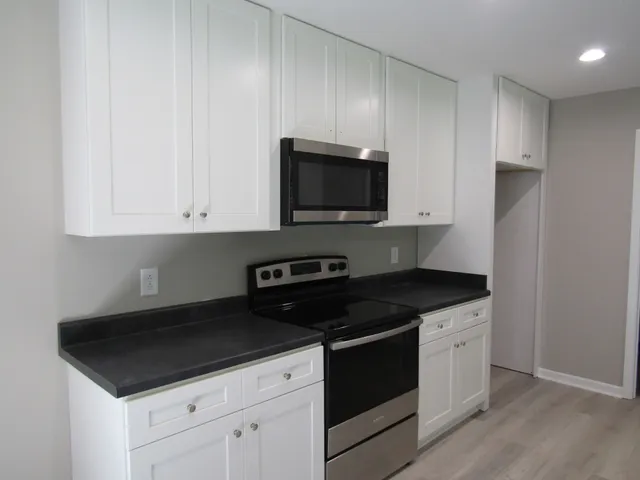 a kitchen with granite countertop white cabinets and black appliances