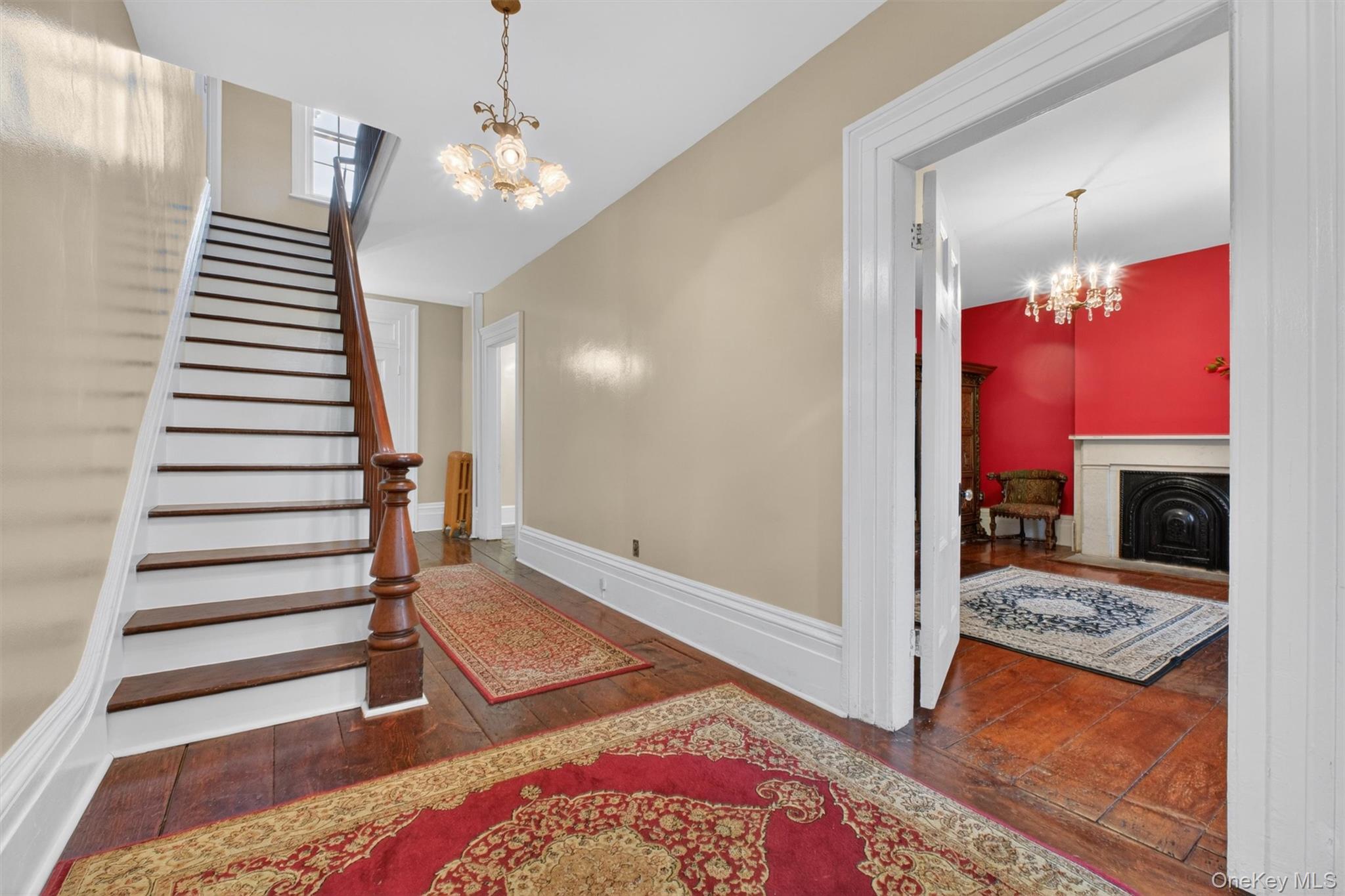 121 Old Glenham Road Fishkill, NY 12524 - Photo 11 of 50 Foyer showcasing hardwood flooring, a classic chandelier, a dark wood staircase with balusters, hallway and door leading to a living area.