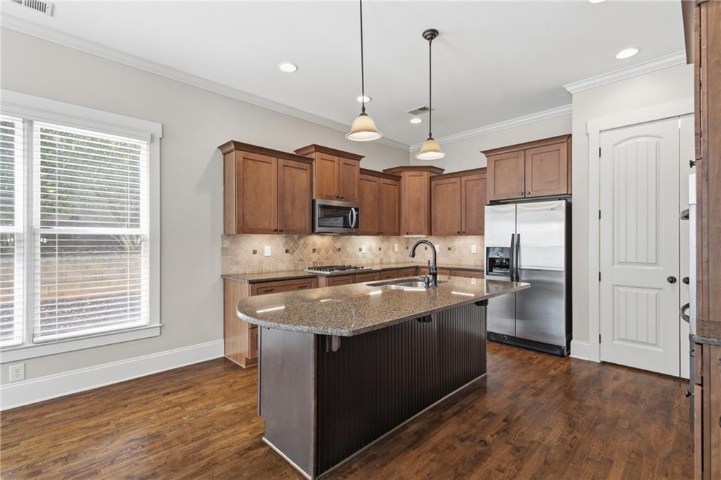 4340 Silent Path Cumming, GA 30028 - Photo 14 of 47 a kitchen with stainless steel appliances granite countertop a sink a stove a refrigerator and island with wooden floor