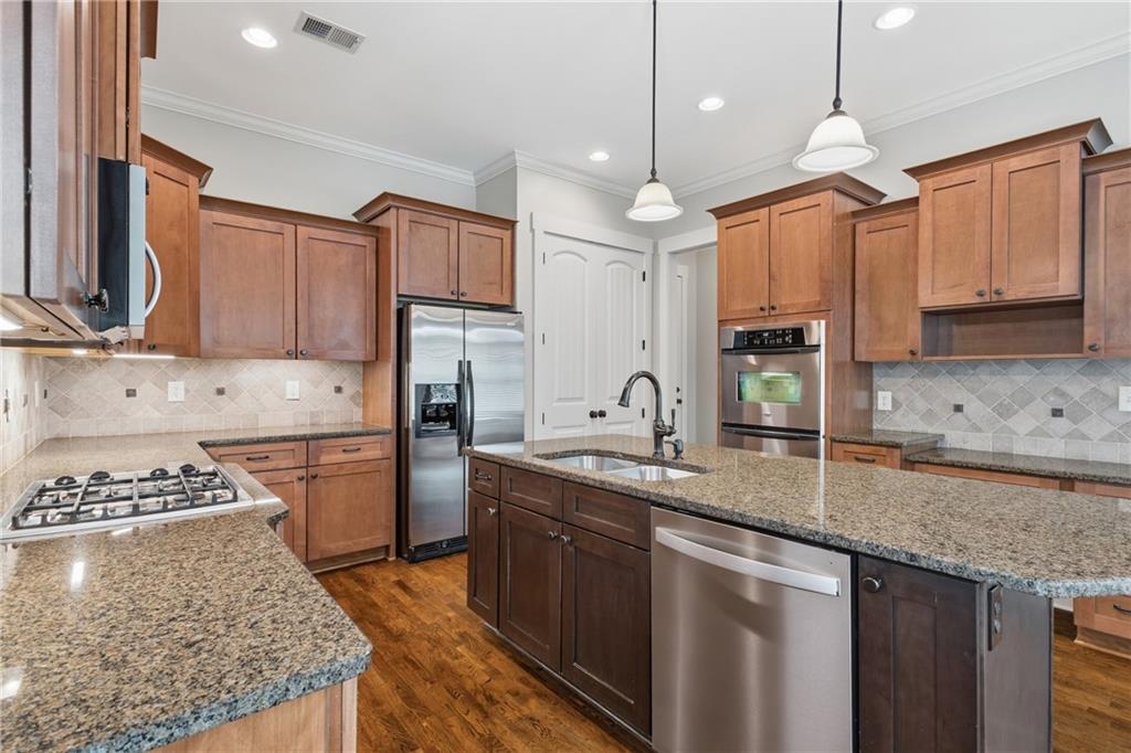 4340 Silent Path Cumming, GA 30028 - Photo 18 of 47 a kitchen with kitchen island granite countertop a sink a counter space appliances and cabinets