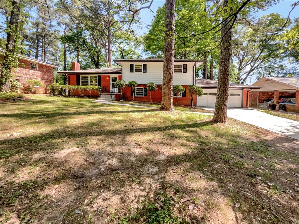 a view of a house with large tree and a yard